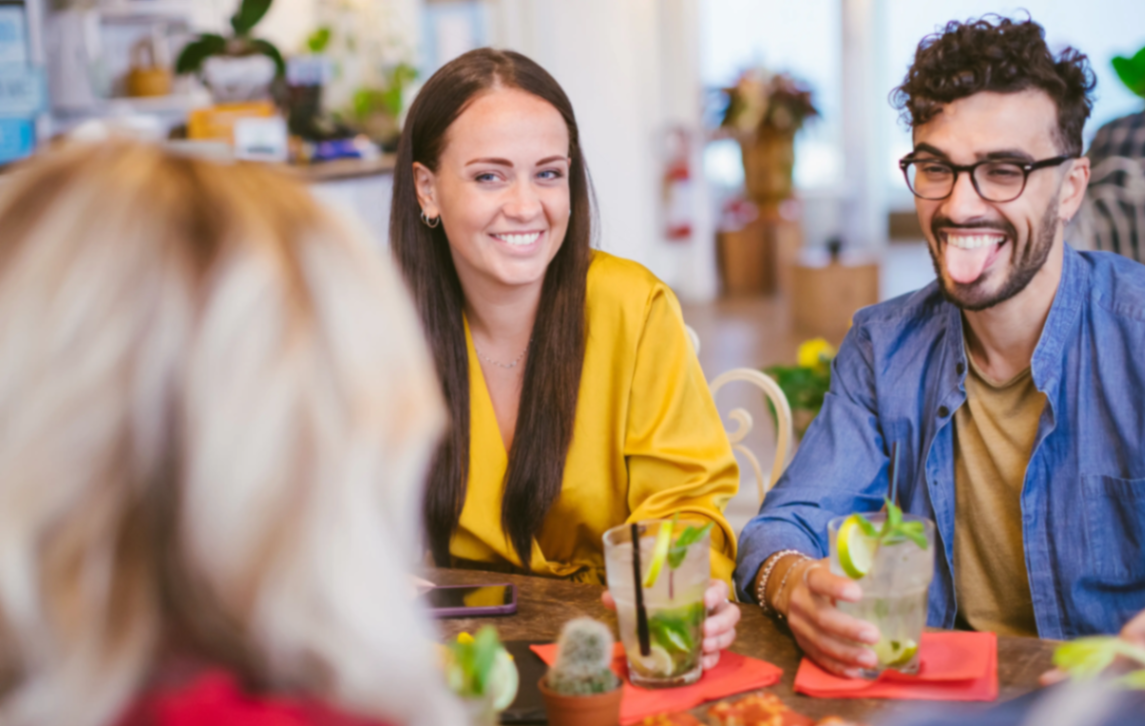 Friends laughing together over drinks at a warm social gathering